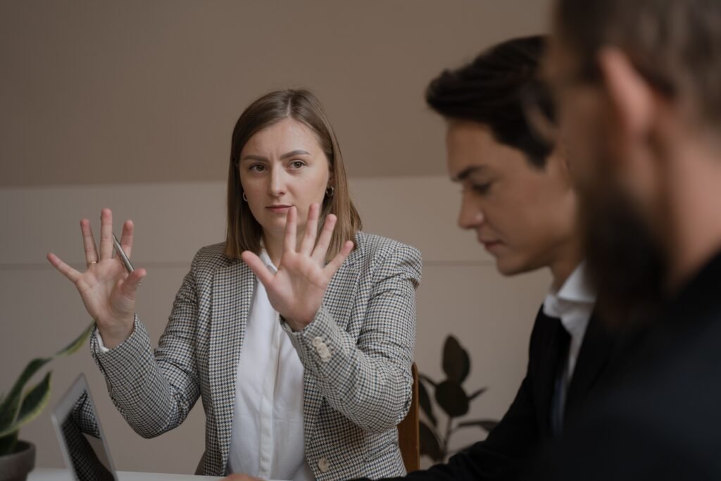 Three professionals in a meeting room engaged in a focused business discussion.